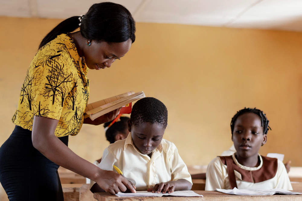 Encadreur ivoirien aidant deux enfants à faire leurs devoirs